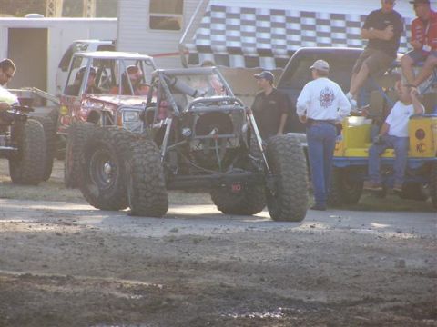 1995 Ford Bronco - Multiple custom off-road vehicles are gathered at an event, with people observing.