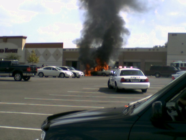 Burning car with police car responding in parking lot