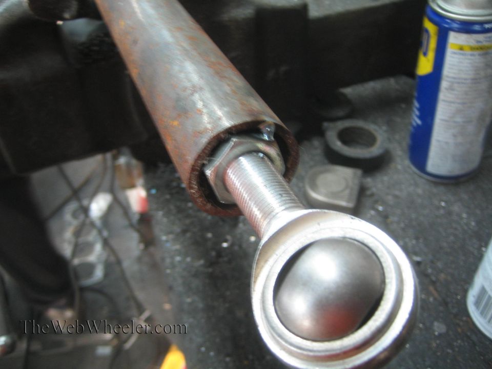 Close-up of a metal rod end joint with a threaded bolt and a ball joint
