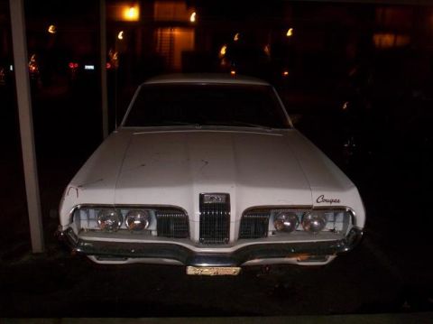 1989 Ford Bronco - Front view of a white 1969 Cougar parked at night, showing its distinctive grille and quad headlights.