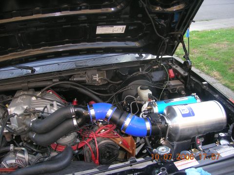 1996 Ford Bronco - The engine bay of a vehicle shows custom modifications, including a large intercooler and intake piping.