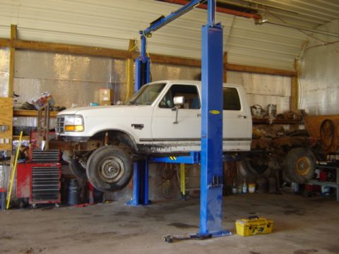 1992 Ford Bronco - White 1992 Ford Bronco undergoing service on a vehicle lift in a workshop.