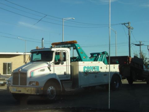 1992 Ford Bronco - A white tow truck with a teal boom and "Cooper" lettering is parked next to another vehicle.