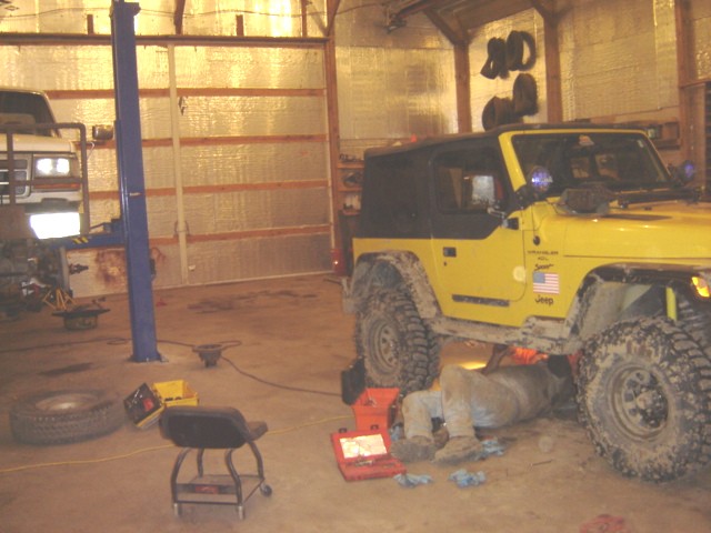 Yellow Jeep Wrangler being worked on in a garage
