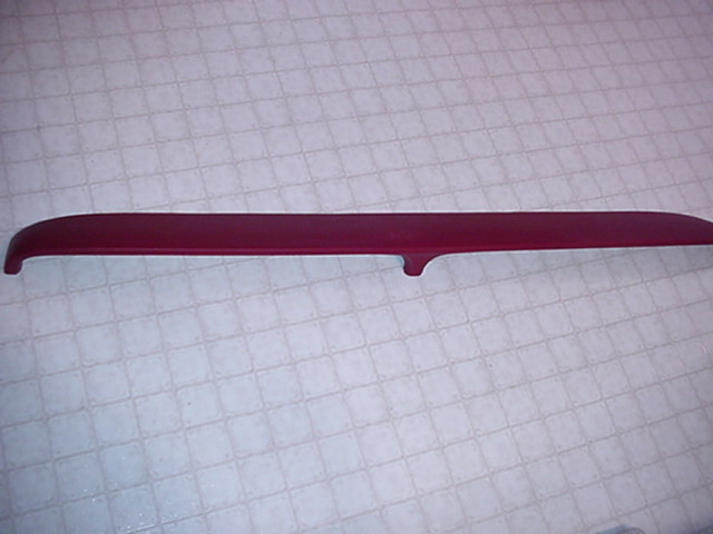 Burgundy molded interior trim panel piece on a tile surface