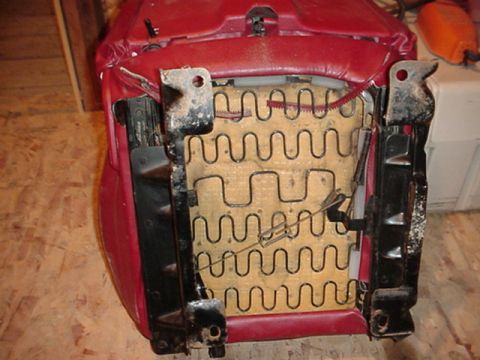 1979 Ford Bronco - The underside of a car seat reveals its internal spring support system and red upholstery.