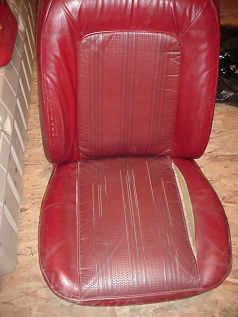 1979 Ford Bronco - This is a red leather car seat, likely from an older vehicle, showing signs of wear.