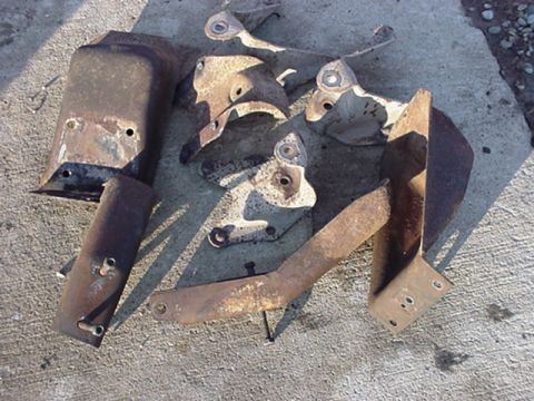 1979 Ford Bronco - Several old, weathered metal components are scattered on a concrete surface.