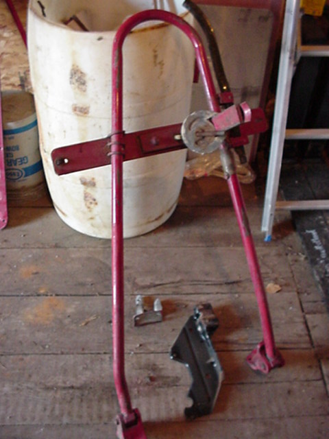 1979 Ford Bronco - Red metal jack mechanism and associated parts are laid out on a wooden floor next to a white bucket.