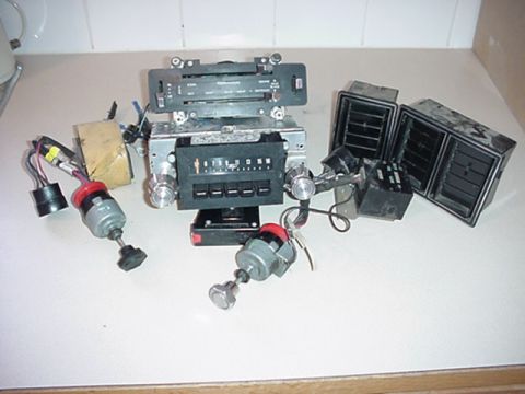 1979 Ford Bronco - Various car interior parts, including a radio and vent assemblies, are laid out on a flat surface.