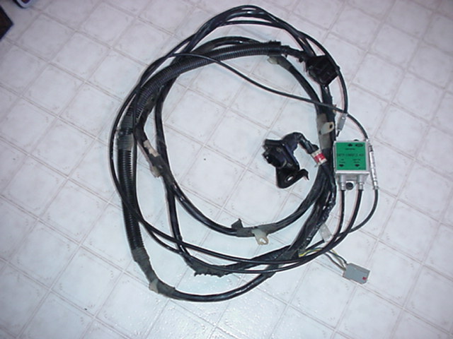 Wiring harness with green electronic module and connectors, laid out on a tiled floor