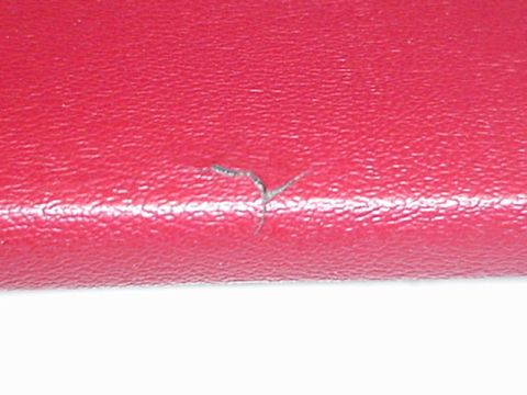 1979 Ford Bronco - Detail of a red textured material showing a small tear and a white stripe, with a website logo visible.