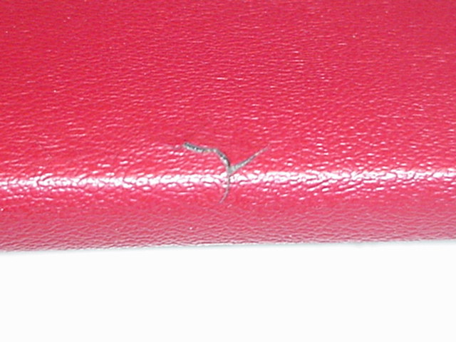 Close-up of a red textured surface with a small tear and a white line. Supermotors.net logo in the corner