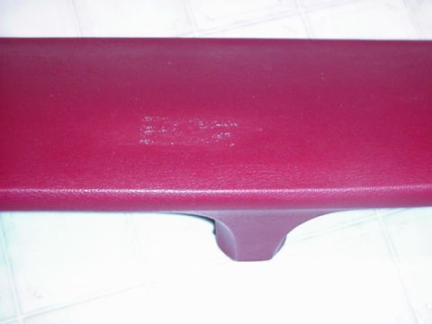 1979 Ford Bronco - A close-up shot of a red automotive interior trim piece, showing some wear.