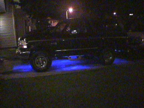 1994 Ford Bronco - A black SUV is parked at night with bright blue lights illuminating the ground underneath it.