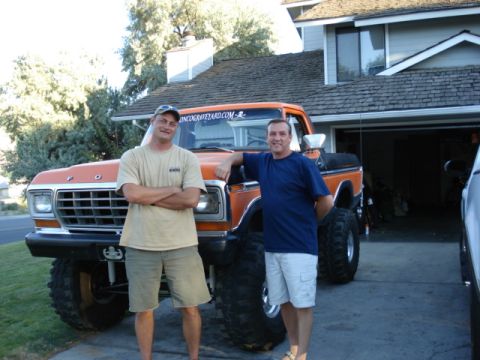 1994 Ford Bronco - This lifted orange Ford truck is shown with two men standing in front of it.