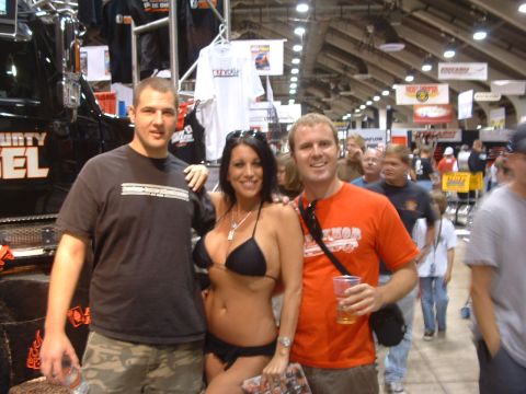 2004 Toyota Tacoma - Three people pose in front of a black truck at an indoor event.