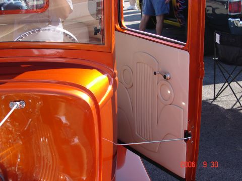 1987 Ford Bronco - A close-up view of the interior of a custom orange hot rod, showing the door panel and part of the steering wheel.