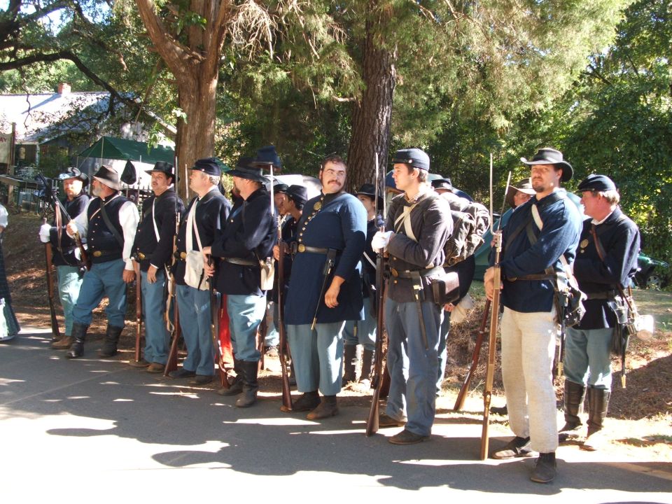 Group of men in Civil War era uniforms standing in formation with rifles