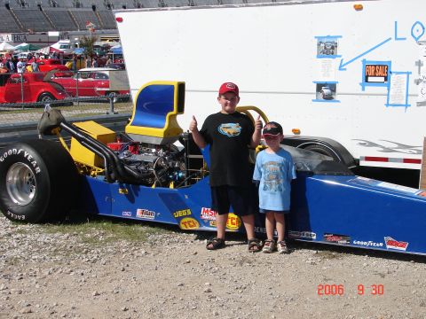 1987 Ford Bronco - Two boys pose with a dragster at an outdoor event. A trailer is visible in the background.
