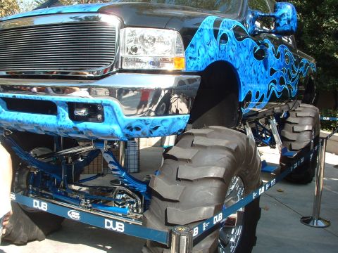 2004 Toyota Tacoma - Customized monster truck with extensive blue flame graphics and DUB branding visible.