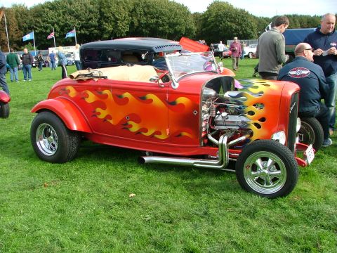 2001 Ford Fiesta - A custom red hot rod with flame decals and an exposed engine sits on display in a grassy field.