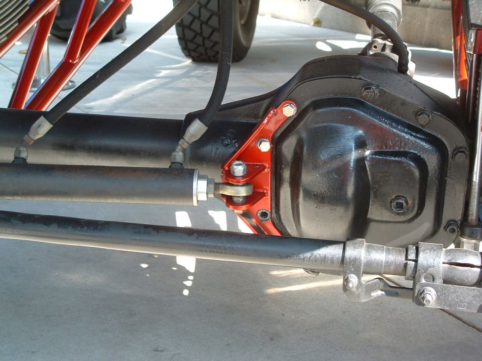 Close-up of a vehicle's rear axle housing with hydraulic steering linkage attached