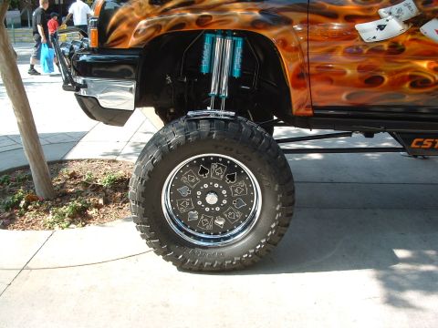 2004 Toyota Tacoma - A heavily modified truck displays custom flame paint and wheel graphics, with visible suspension upgrades.