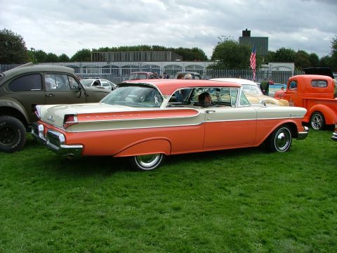 2001 Ford Fiesta - A classic 1957 Mercury sedan, painted in a distinctive orange and cream two-tone, is parked on a grassy field.