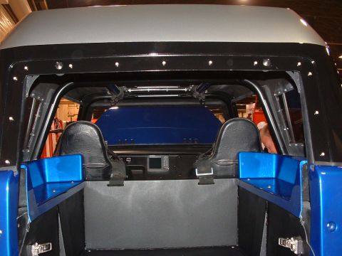 2004 Toyota Tacoma - The interior of a modified pickup truck features custom seats and a roll cage, with a blue bed cover visible.