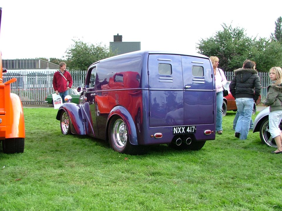 Purple custom van with chrome wheels and dual exhaust pipes, seen from the rear