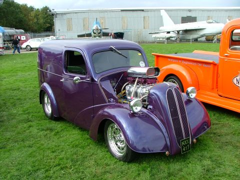 2001 Ford Fiesta - A custom purple panel van with a prominent engine sits on display next to an orange truck.