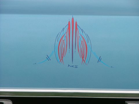 1970 Ford Ranchero - A close-up of custom pinstripe artwork in red and blue adorns the side of a light blue vehicle, signed by the artist.