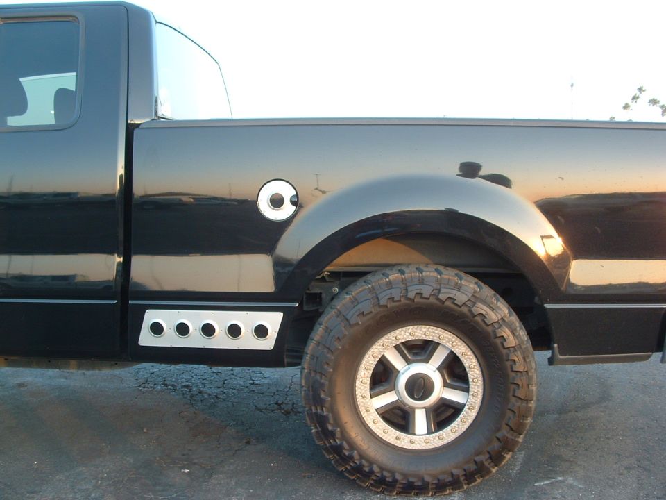 Black pickup truck side view showing fuel door, fender, and wheel