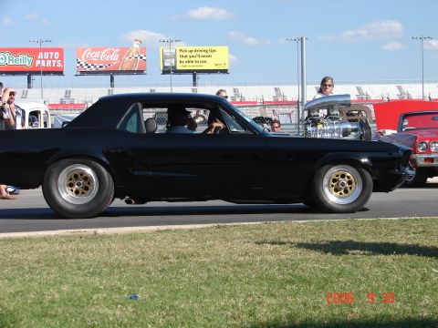 1987 Ford Bronco - Custom coupe with exposed supercharger at a track event. A second vehicle is partially visible.