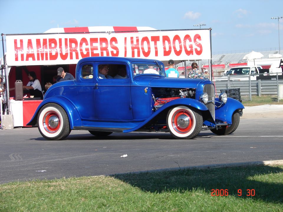 blue hot rod coupe driving past a hamburger stand