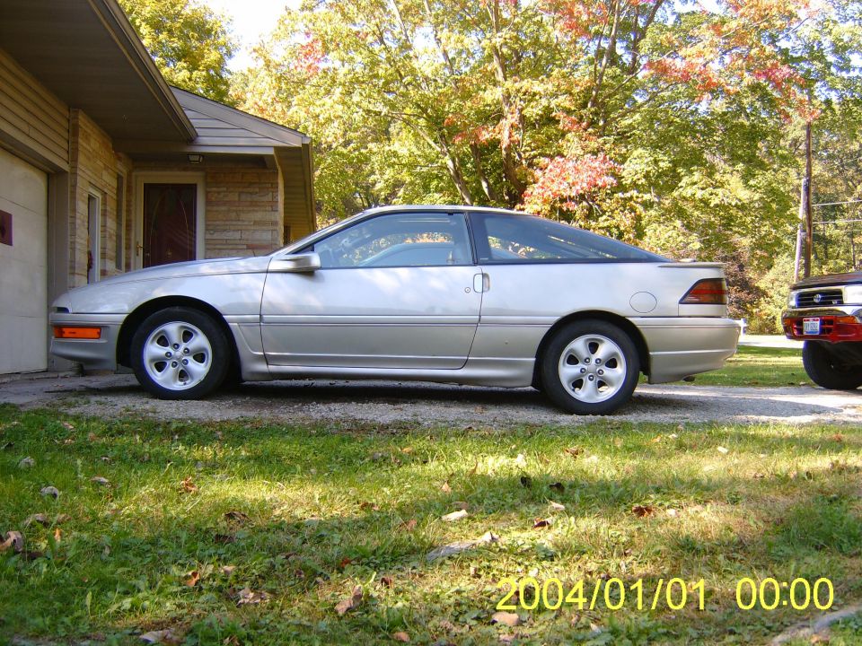 Silver 1990 Ford Probe coupe parked on a gravel driveway, side view