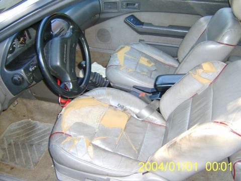 1990 Ford Probe - Interior view of a 1990 Ford Probe, showing the dashboard, steering wheel, and front seats with significant wear.