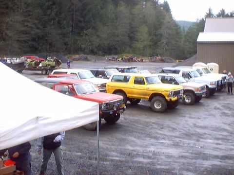 1976 Ford F-100 - A line of trucks and SUVs are parked in an outdoor lot, with a red Ford F-100 in the foreground.