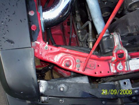 1990 Ford Mustang - Close-up view of the engine bay, showing red structural components and a chrome intake pipe.