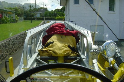 1991 Ford Bronco - Firefighter gear is secured on the ladder of a truck, with buildings and trees in the background.