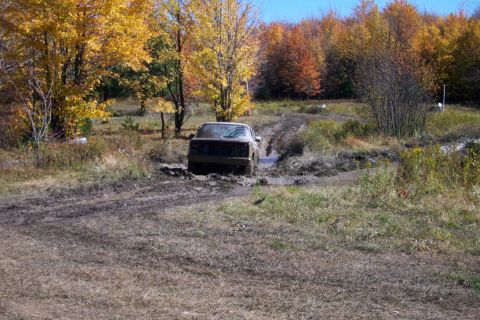 1979 Ford Bronco - A truck navigates a muddy off-road trail during autumn.