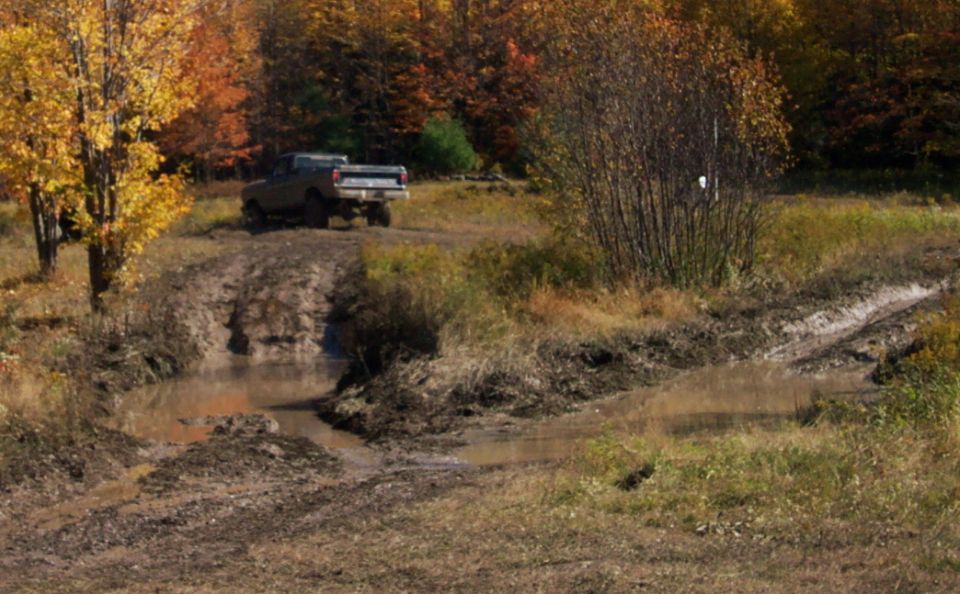 Pickup truck driving through mud and water on an off-road trail during autumn