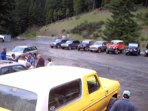 1976 Ford F-100 - A yellow SUV with a white top is parked in a lot with several other vehicles, including SUVs and trucks.
