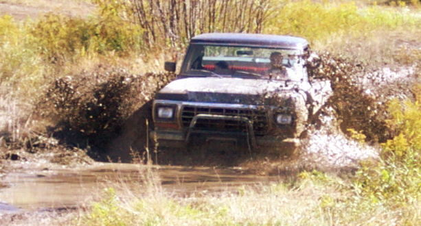 Ford Bronco stuck in mud, front view. Grille suggests 1978 model year