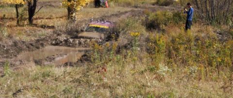 1979 Ford Bronco - A purple off-road vehicle, labeled 'SMUGGER', is stuck deep in a muddy ditch during an outdoor event.
