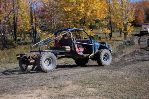 1979 Ford Bronco - A heavily modified off-road vehicle with a roll cage is seen on a dirt track, with another vehicle in the background.