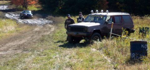 1979 Ford Bronco - A Jeep Cherokee XJ navigates a muddy off-road course with another vehicle in the background.
