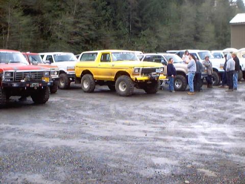 1976 Ford F-100 - A group of trucks are parked in an outdoor lot, with several people gathered near them.