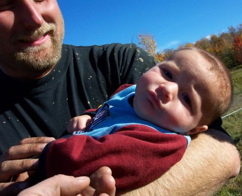1979 Ford Bronco - A man holds a baby outdoors with autumn trees in the background.